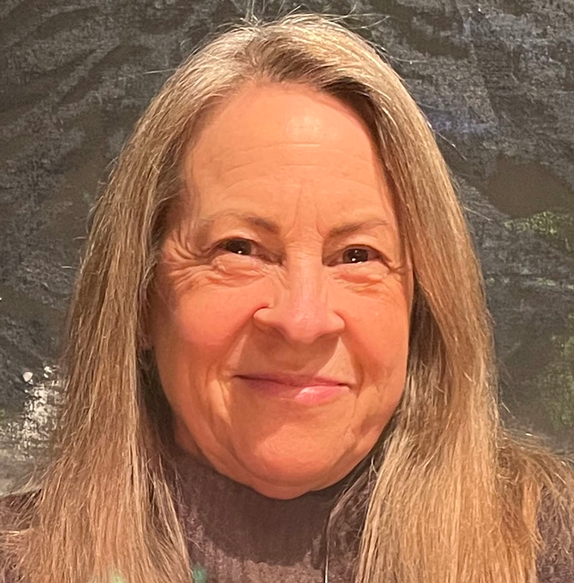 A person with long blonde hair smiling to the camera